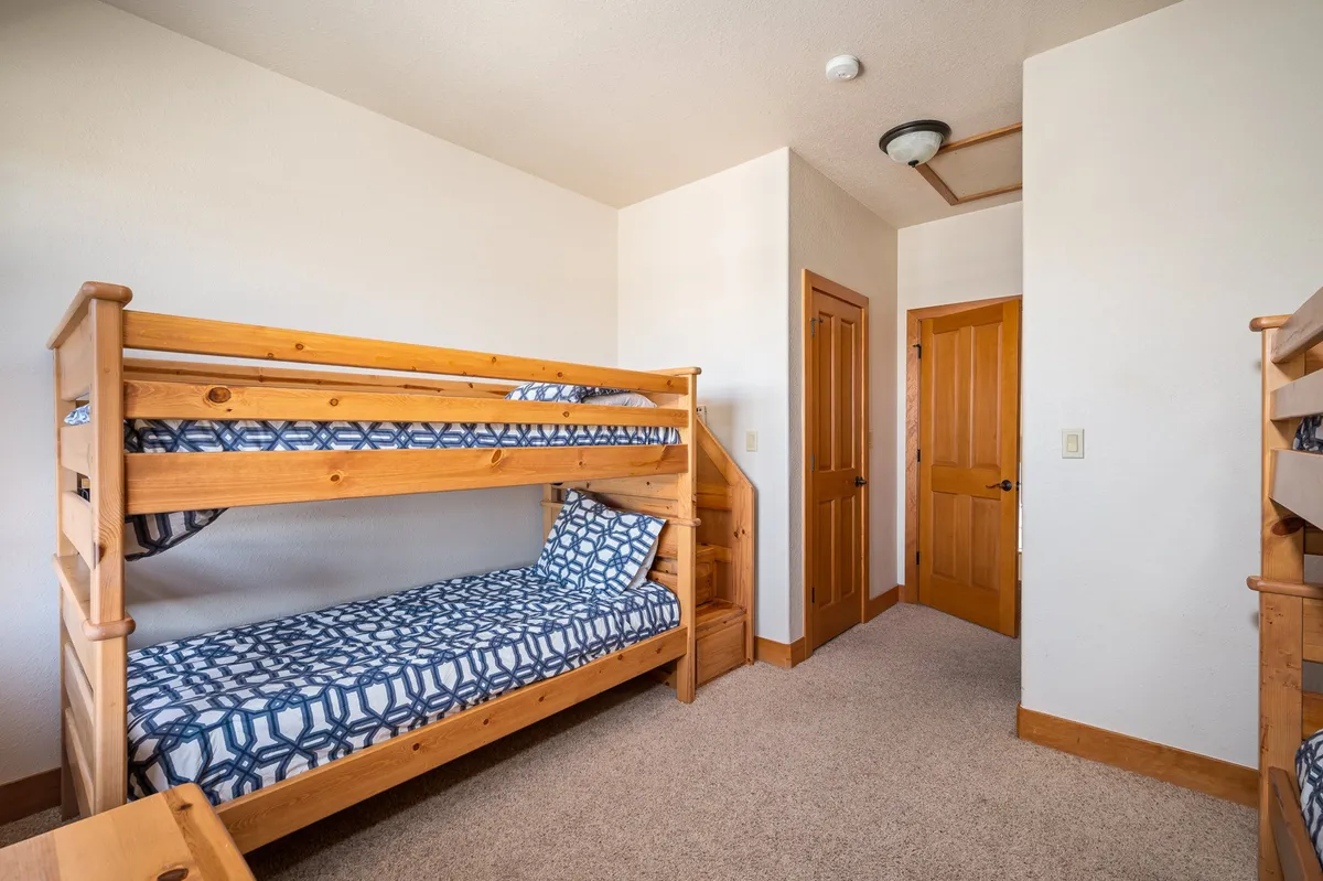 This playful bedroom features sturdy bunk beds with decorative pillows and a wooden door, suggesting a fun and relaxed space perfect for kids. The setup encourages late-night conversations, story time, and sibling bonding.