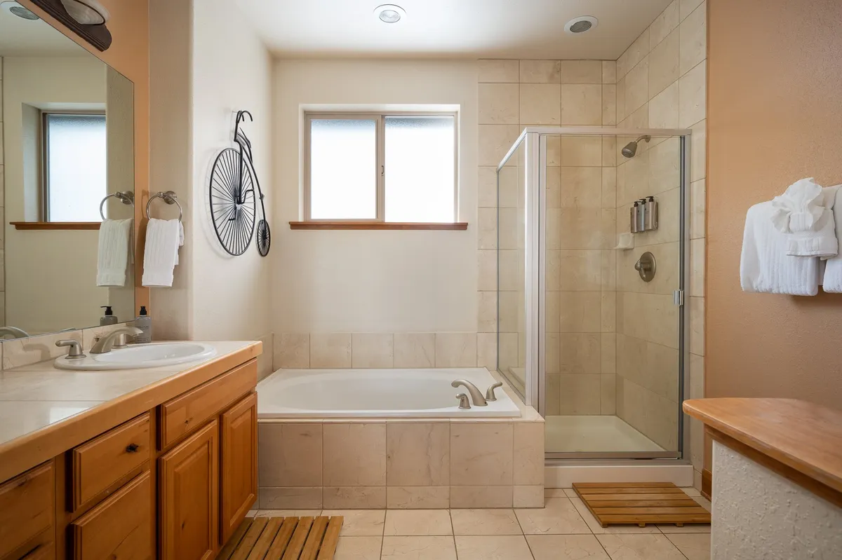 A serene bathroom space featuring a luxurious bathtub, walk-in shower, vanity mirror, and natural wooden accents that create a tranquil, spa-like environment for self-care and relaxation.